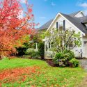 White two-story house with autumn leaves and garden, near Walker Plumbing's service area.